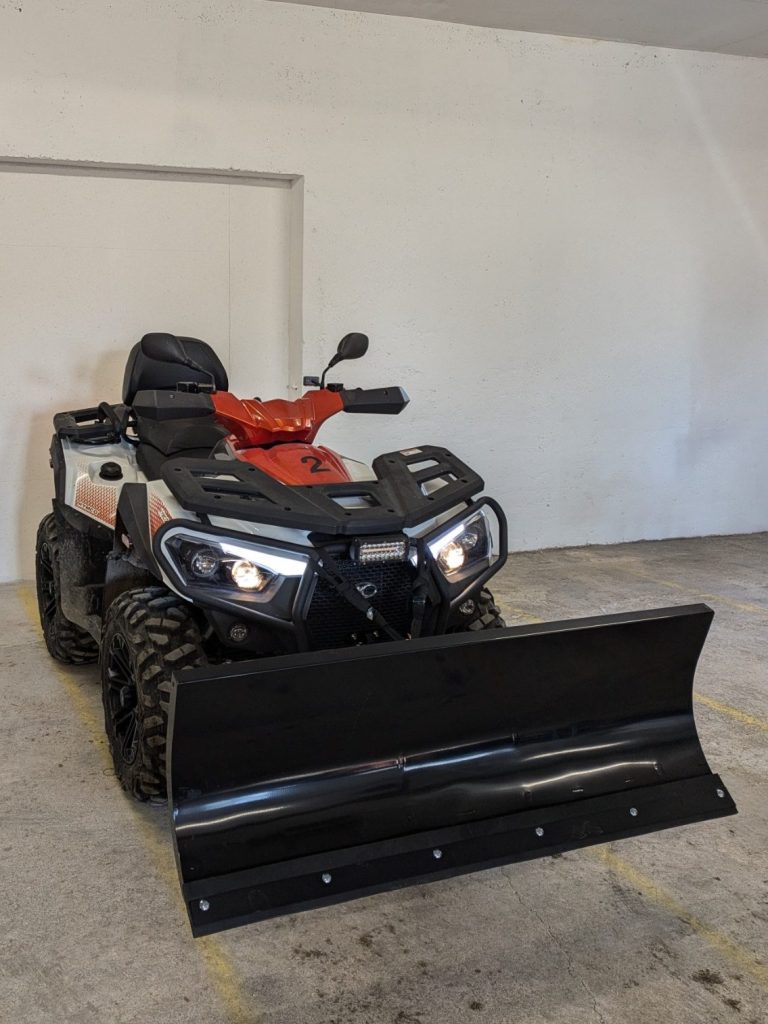Ein Quad mit Schneepflug in einer Garage.